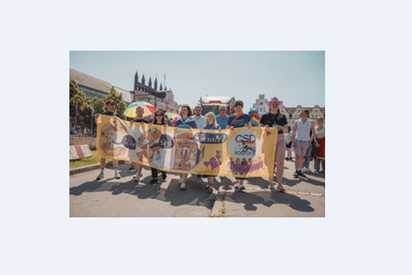 viele Menschen demonstrieren, die vorderen tragen ein Banner, Regenbogenfarben