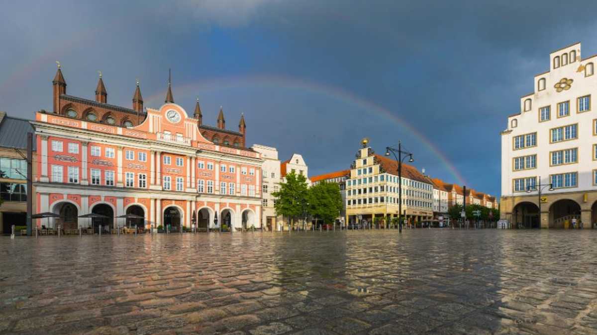 Rathaus Rostock mit Regenbogen im Hintergrund